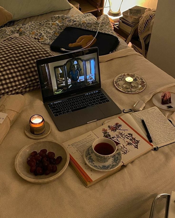 This may contain: an open laptop computer sitting on top of a bed next to plates and cups filled with food