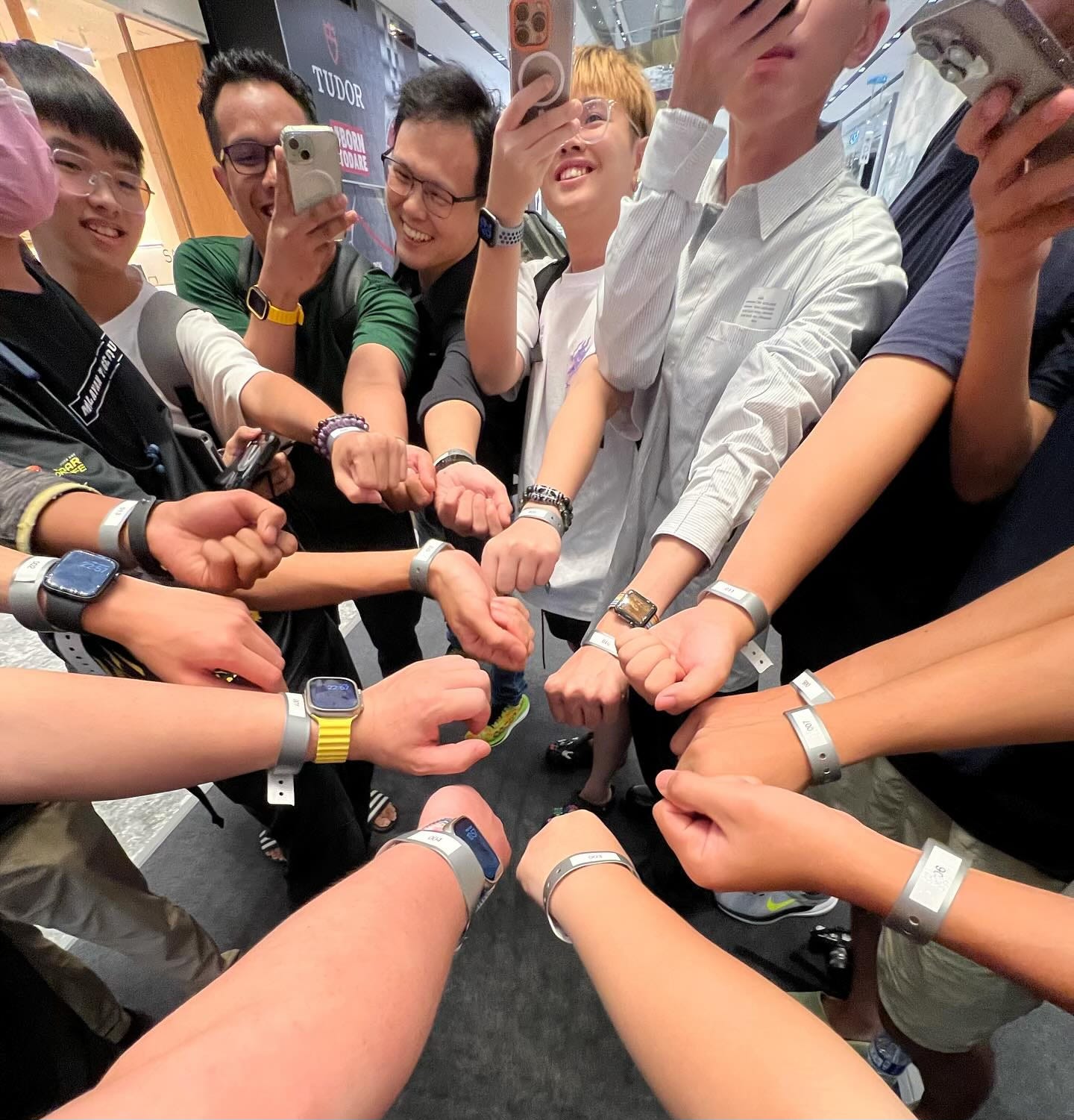 Some of the earliest fans waiting in line for the opening of Apple The Exchange TRX show off their wrist bands while taking a group photo.