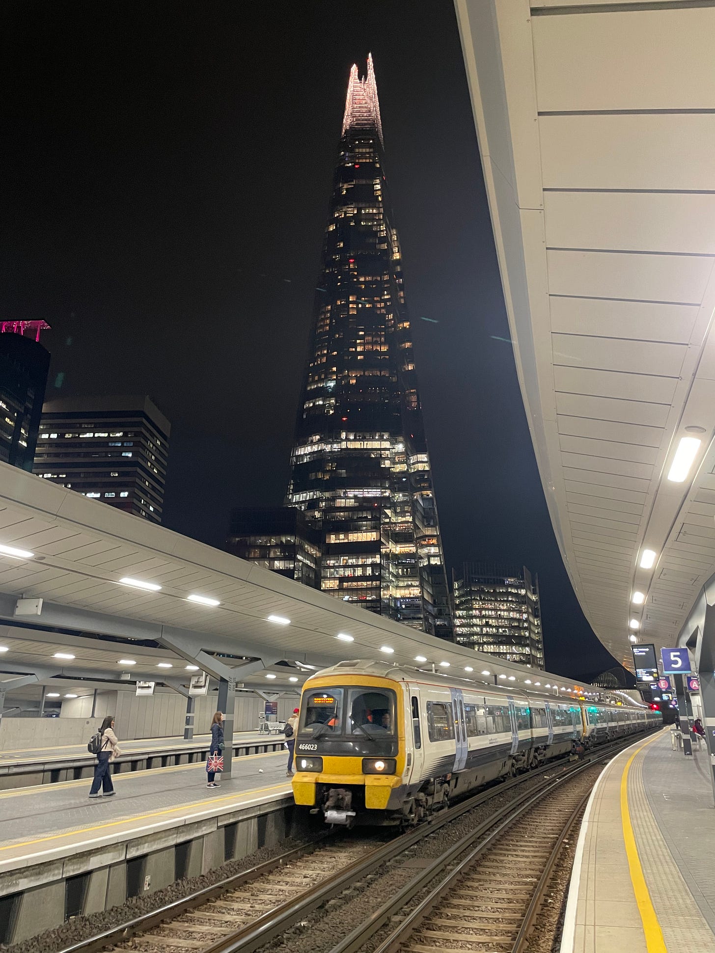 a southeastern train in the platform at london bridge station. the shard is in the background