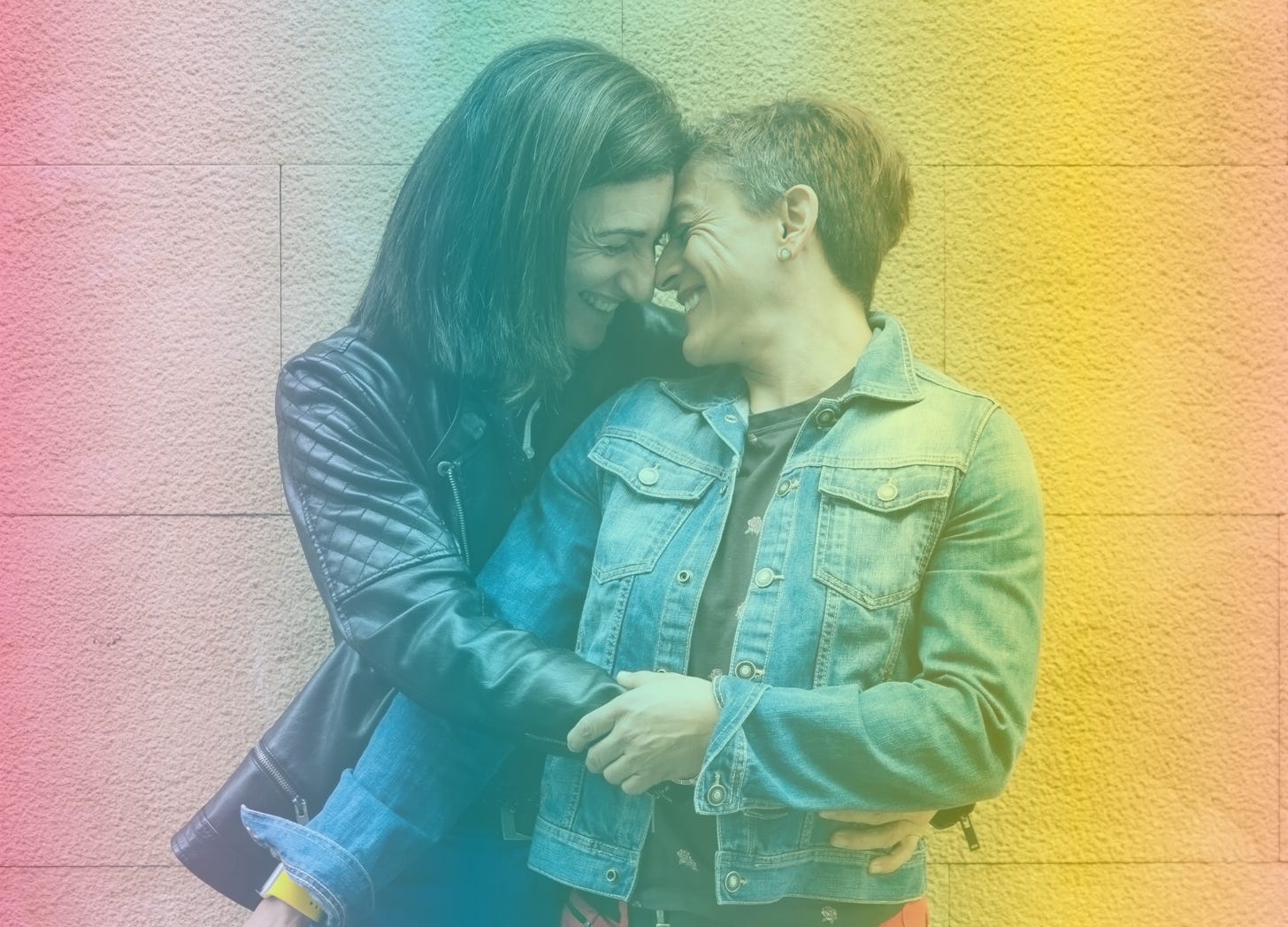 A rainbow-filtered photograph of two middle-aged women cuddling with each other