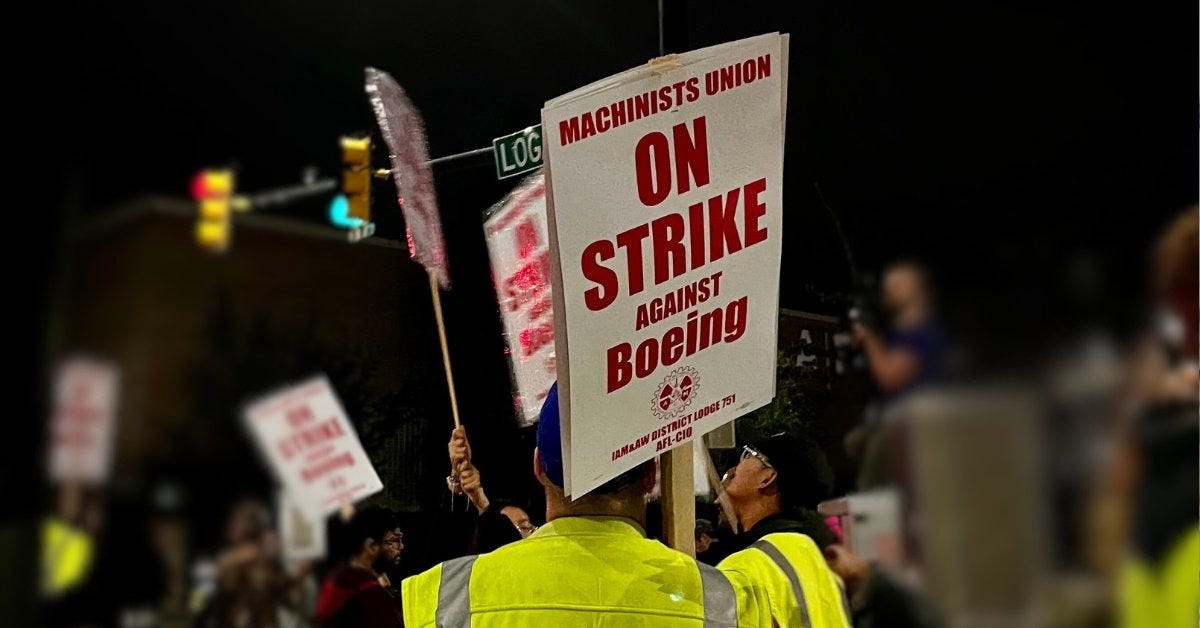 A Machinist carries a picket sign on the strike line in Renton