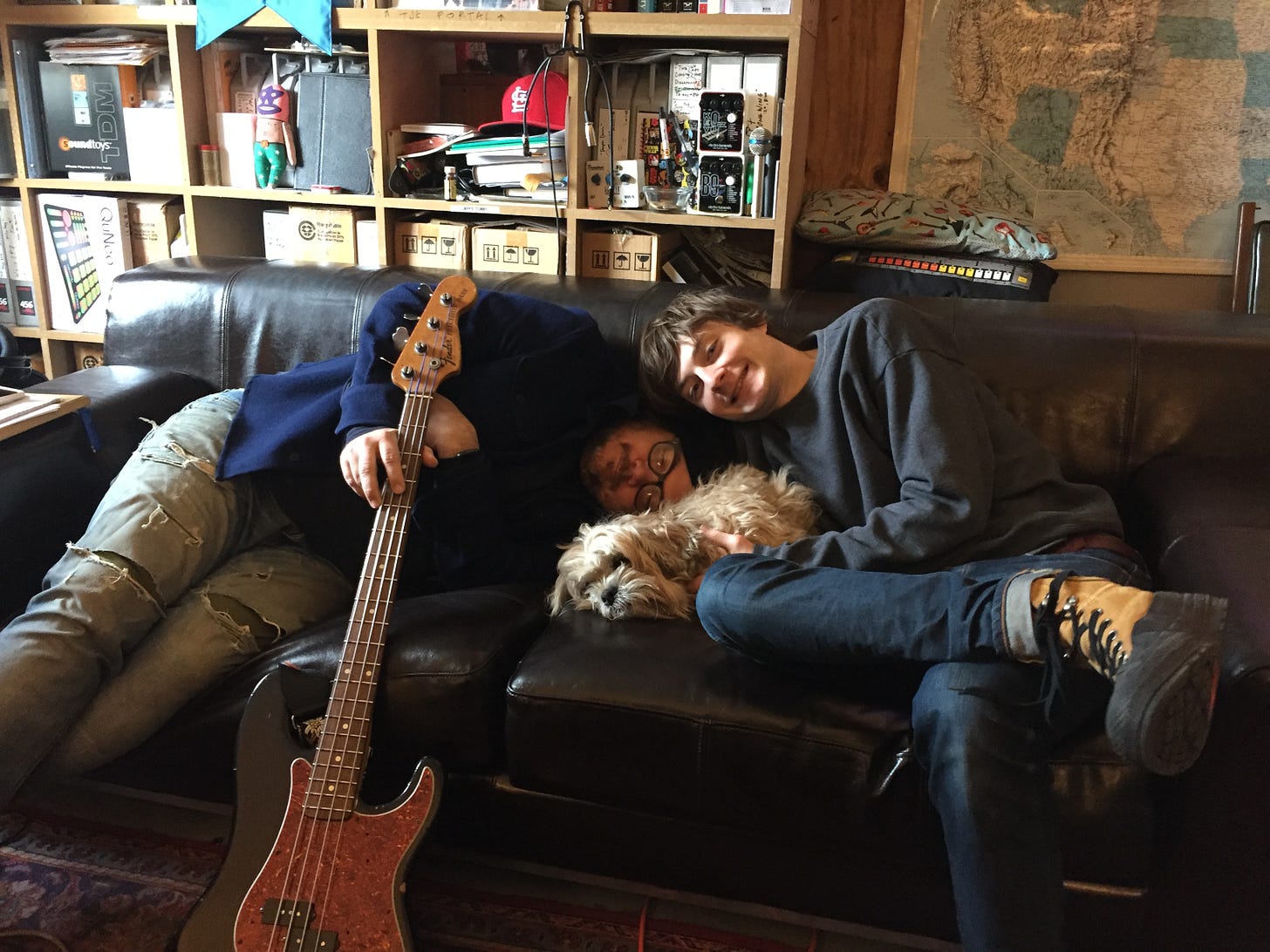 Jeff, Spencer, and a fluffy small dog named Dwight pose on the couch at the Wilco Loft.