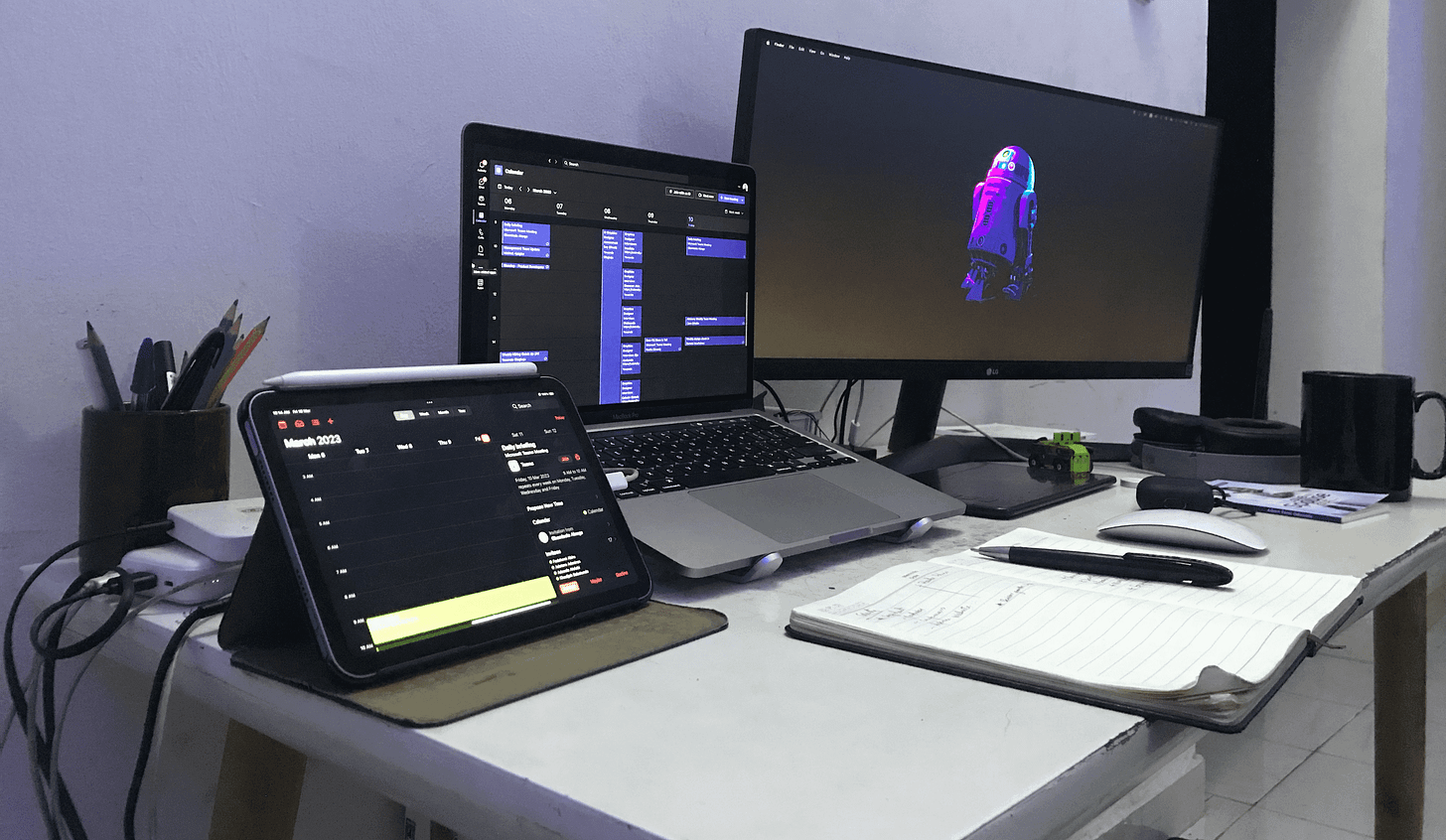 Dumebi Workspace showing a includes a 2022 M2 MacBook Pro, a 29” LG ultra wide monitor, an Apple keyboard with numeric keypad, the Apple mouse, a Huion graphic tablet, and an iPad mini 6 with an Apple Pencil