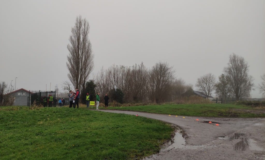 View of the finish line, with grass bordering the park and puddles settling by the side from rain in the week.