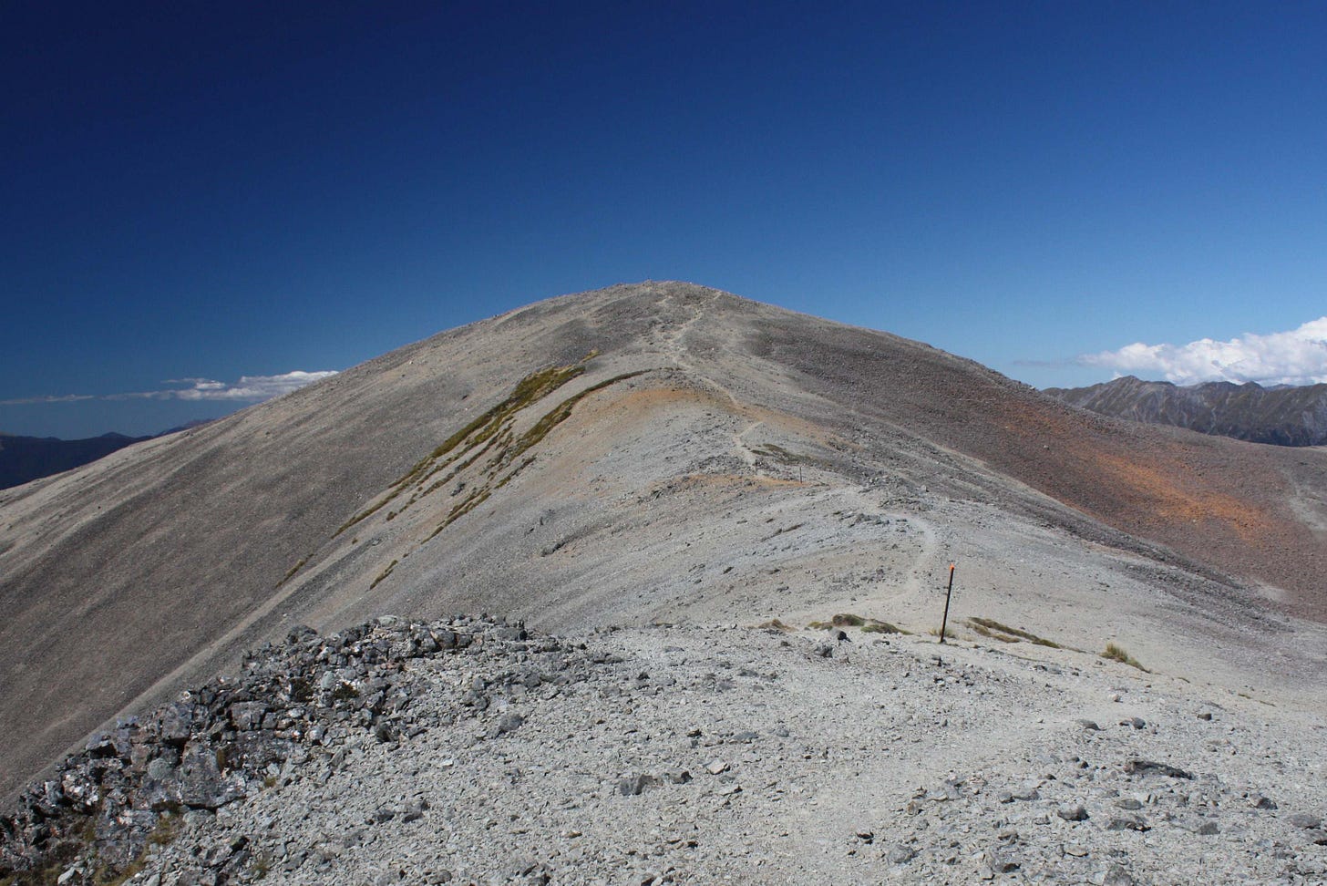 A gravelly ridge in Nelson Lakes National Park, with a track winding upwards under a blue sky
