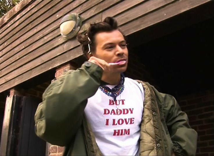Harry Styles brushing his teeth while wearing a t-shirt that reads BUT DADDY I LOVE HIM.