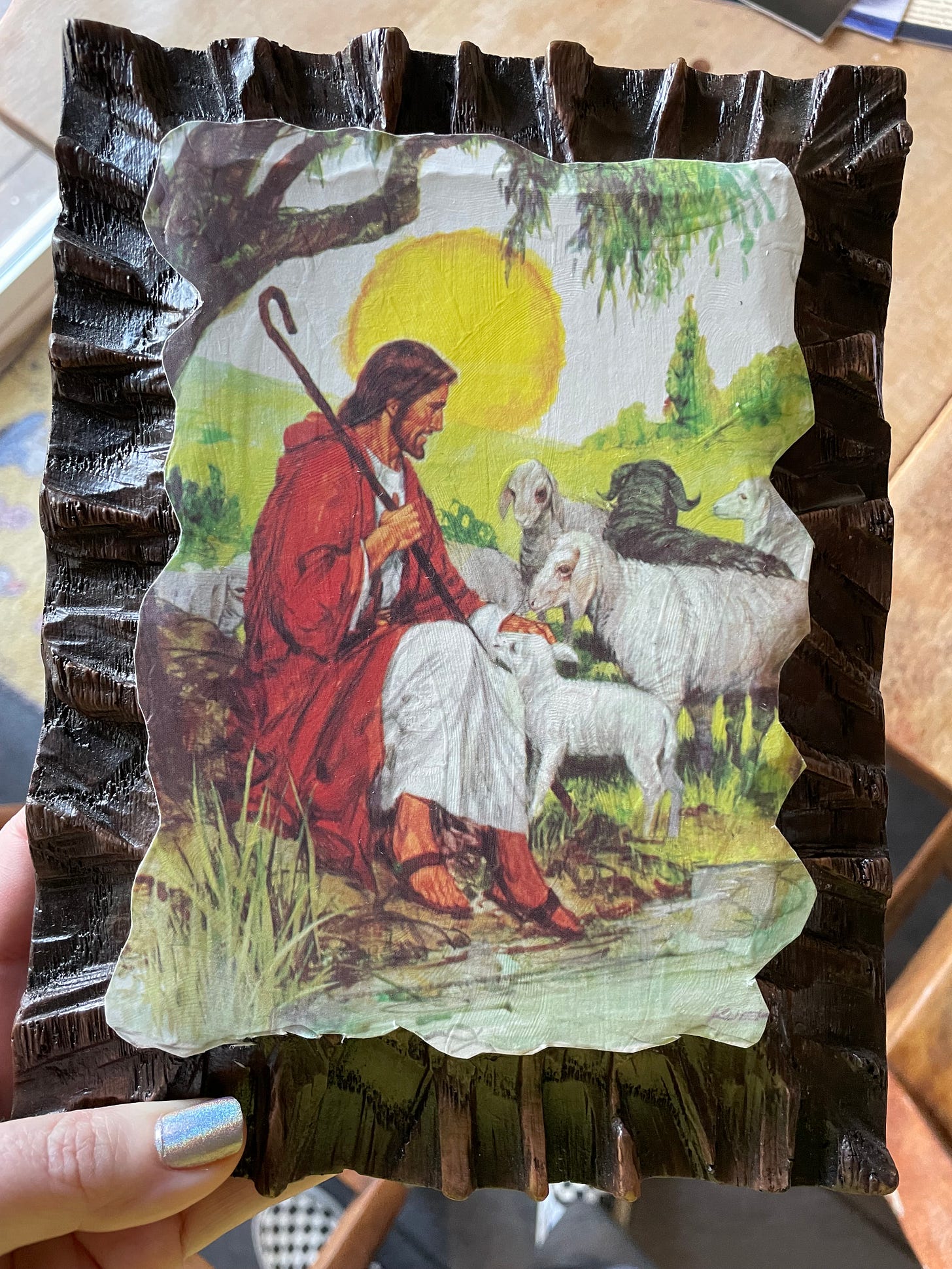 an old timey image of Jesus as a shephaerd surrounded by sheep. all the white sheep are looking at him while the lone black sheep stares off into the distance