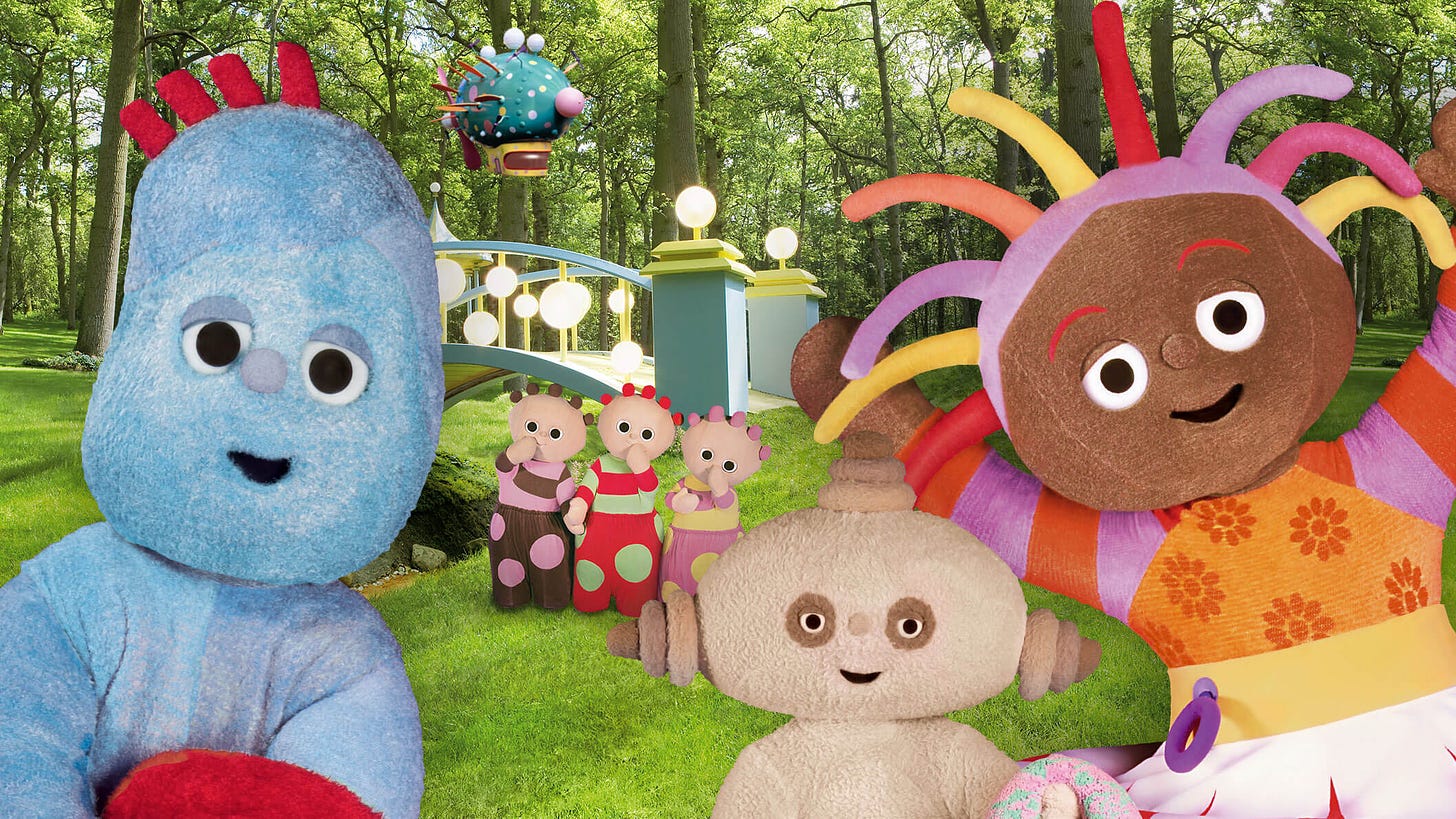 A close up of a blue character, a beige character and a girls with colourful stringy hair. Behind them is a green park and three other characters.