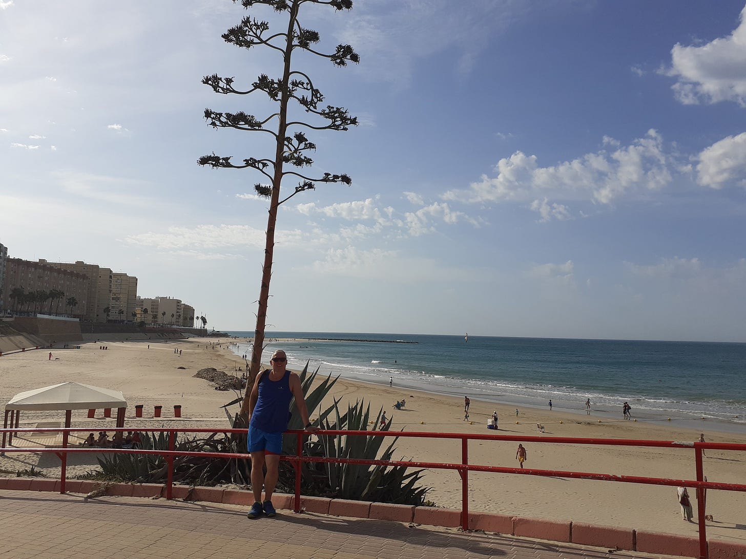 Neil Mapes infront of a large cactus and beachfront, sand and sea, at Cadiz in Spain