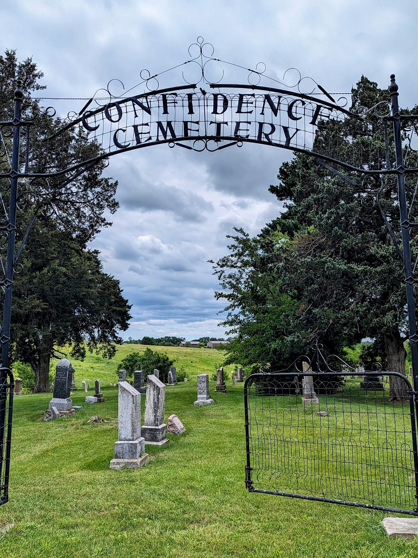 An old cemetery with an iron gate that says 'Confidence Cemetery'