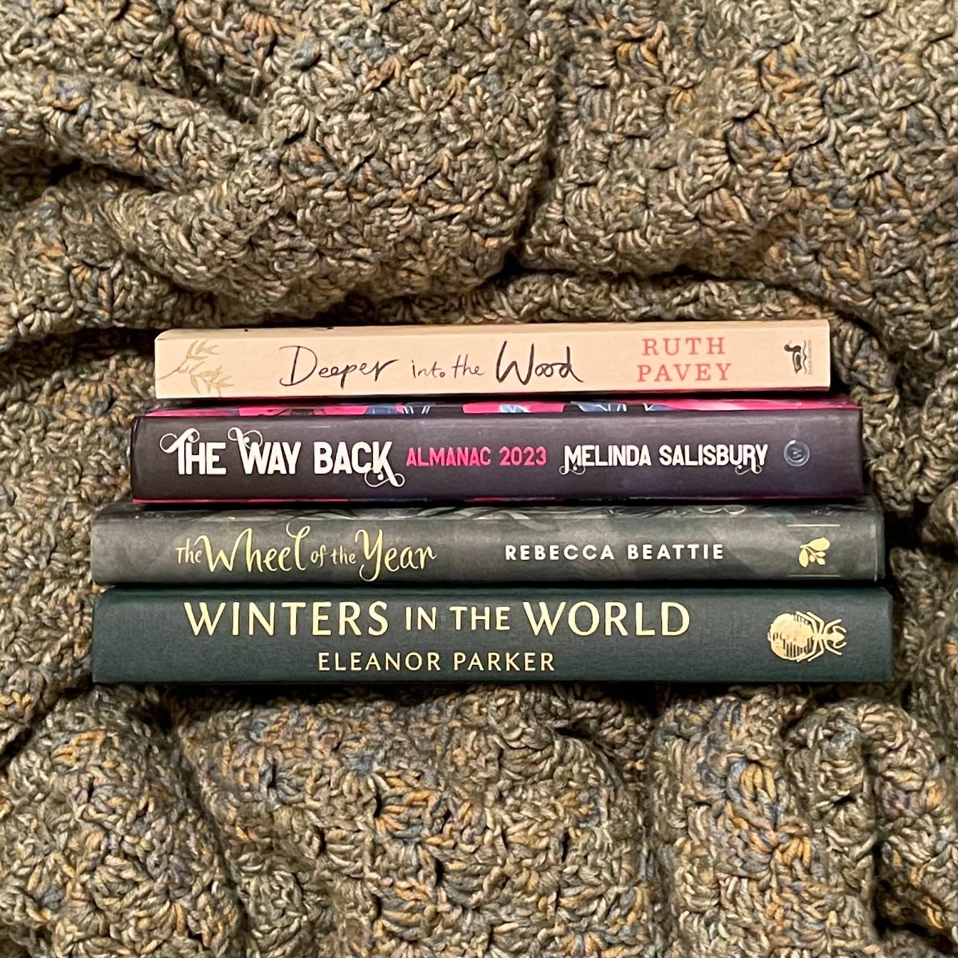 Photo of a stack of books surrounded by the folds of crocheted blanket