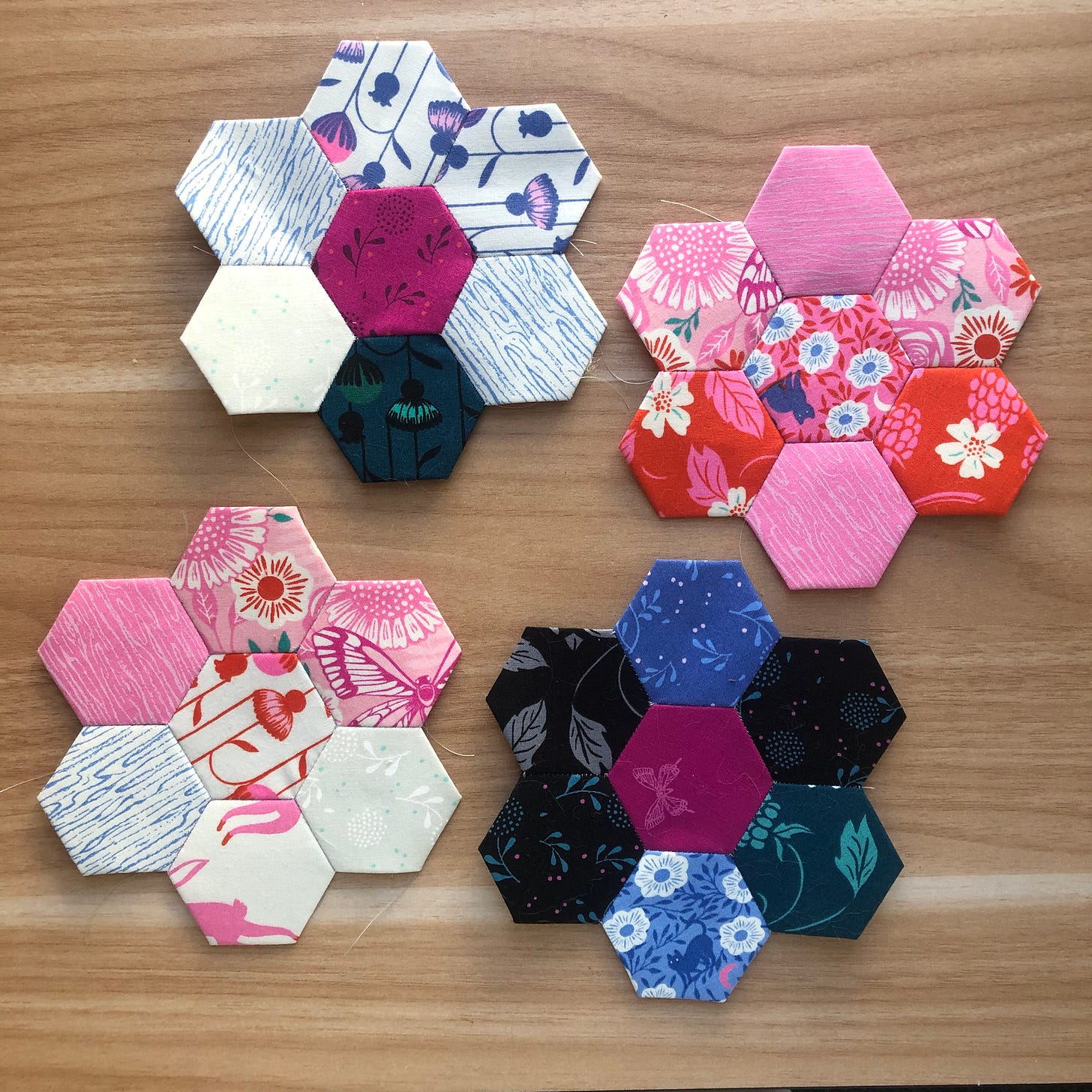 four colorfully sewn hexagonal flower groupings against a wooden background