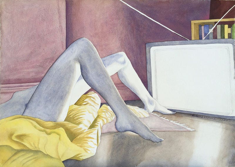 Descrição da imagem: Mulher nua com pernas dobradas sob colcha amarela e tapete rosa claro. Um dos pés apoiado abaixo da TV. Parede ao lado é rosa e o restante em tons de cinza e branco