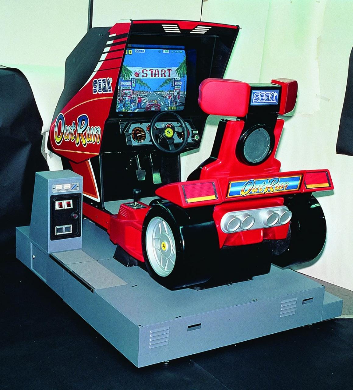 A photo of the deluxe cabinet of the original OutRun, which not only was a sit-down model with the hood of the car and a windshield used to tuck the monitor away inside, but also featured back tires.
