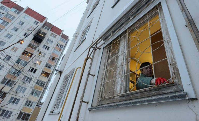 A woman removes broken glass next to a damaged multi-storey apartment block following a reported drone attack in Voronezh, Russia January 16, 2024. REUTERS/Stringer