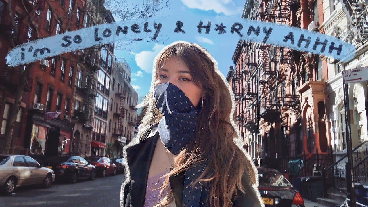 a day in my life in quarantine *alone in nyc* - YouTube screenshot of Ashley wearing a face covering with the text "i'm so lonely & h*rny ahhhh"