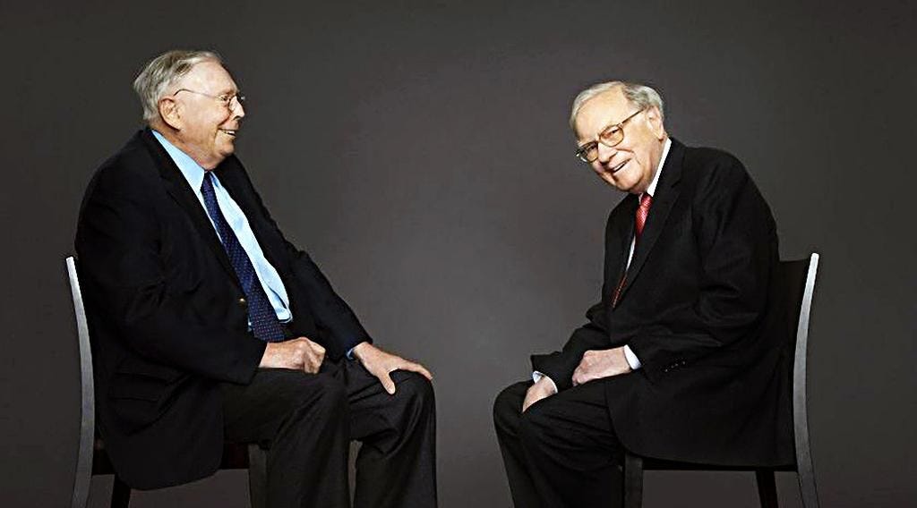 Warren buffet and Charlie Munger sitting in chair in front of each other, happily smiling