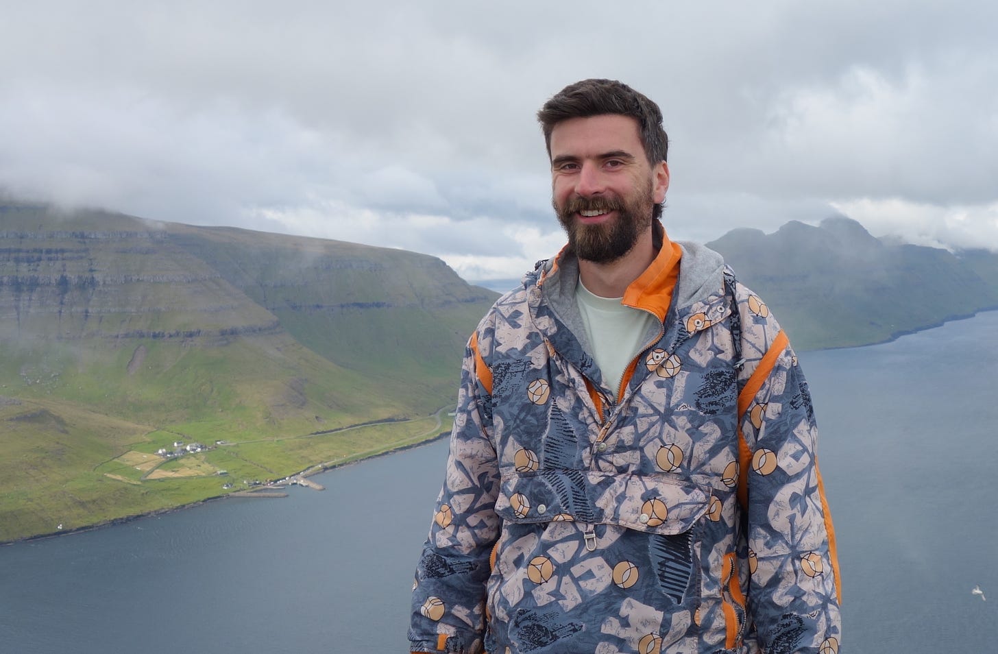 Zac Crellin, creator of Open Newswire stands smiling in front of a natural landscape.