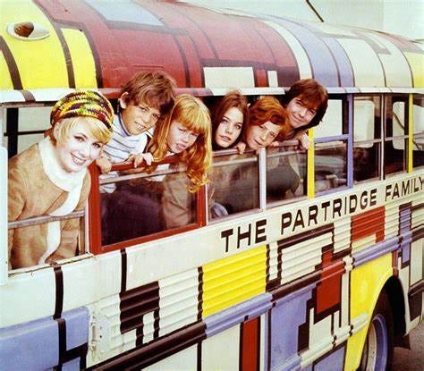 a brightly painted school bus with a mom and five children of various ages poking their heads out the windows