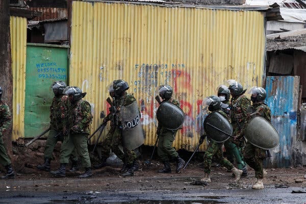 Officers in gear near a wall with graffiti.