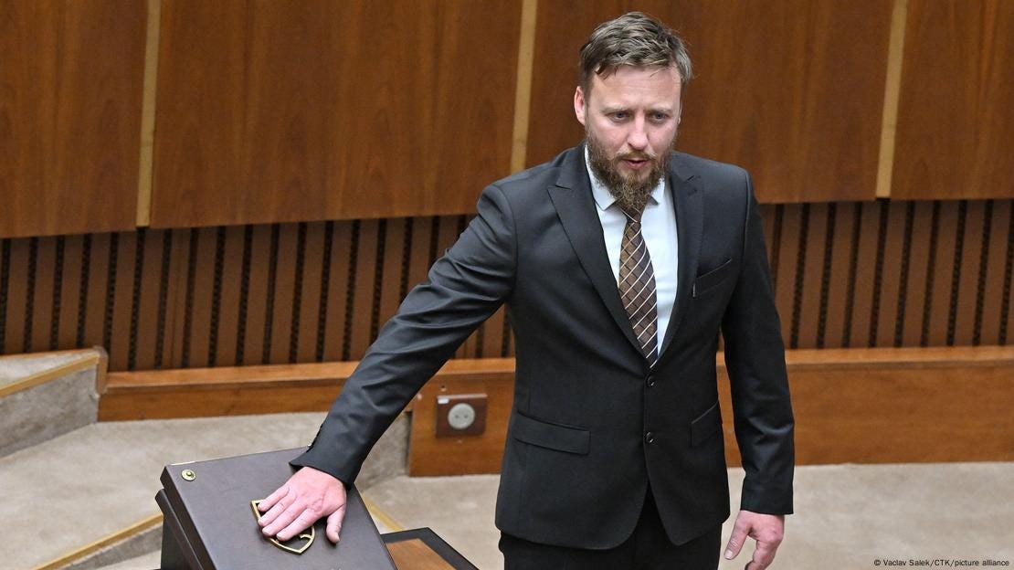 A bearded man in a dark suit (MP Peter Kotlar) puts his hand on the Constitution of Slovakia during his swearing-in ceremony in the Slovak Parliament