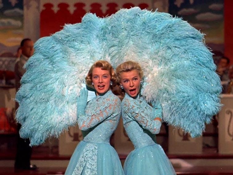 Rosemary Clooney and Vera-Ellen wearing powder blue Edith Head dresses and holding large blue feather fans.