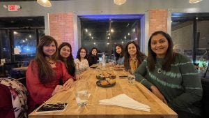 Seven women smile at a table.