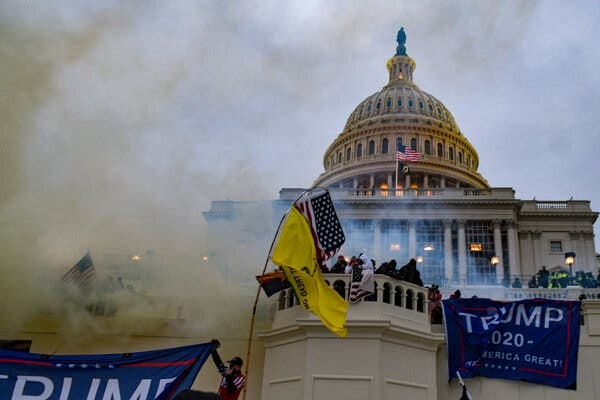 Rioters storming the Capitol on Jan. 6, 2021, as a cloud of smoke is seen with Trump flags.