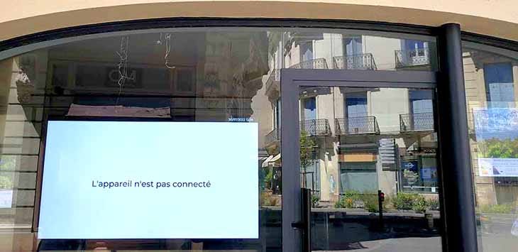 Photo of a video screen in a shop window that shows an error message reading "L'appareil n'est pas connecté".