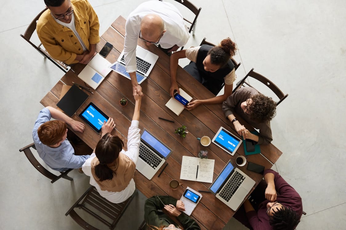 Free Top view of a diverse team collaborating in an office setting with laptops and tablets, promoting cooperation. Stock Photo