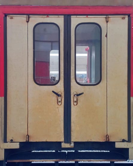 porte di un treno color crema su sfondo rosso