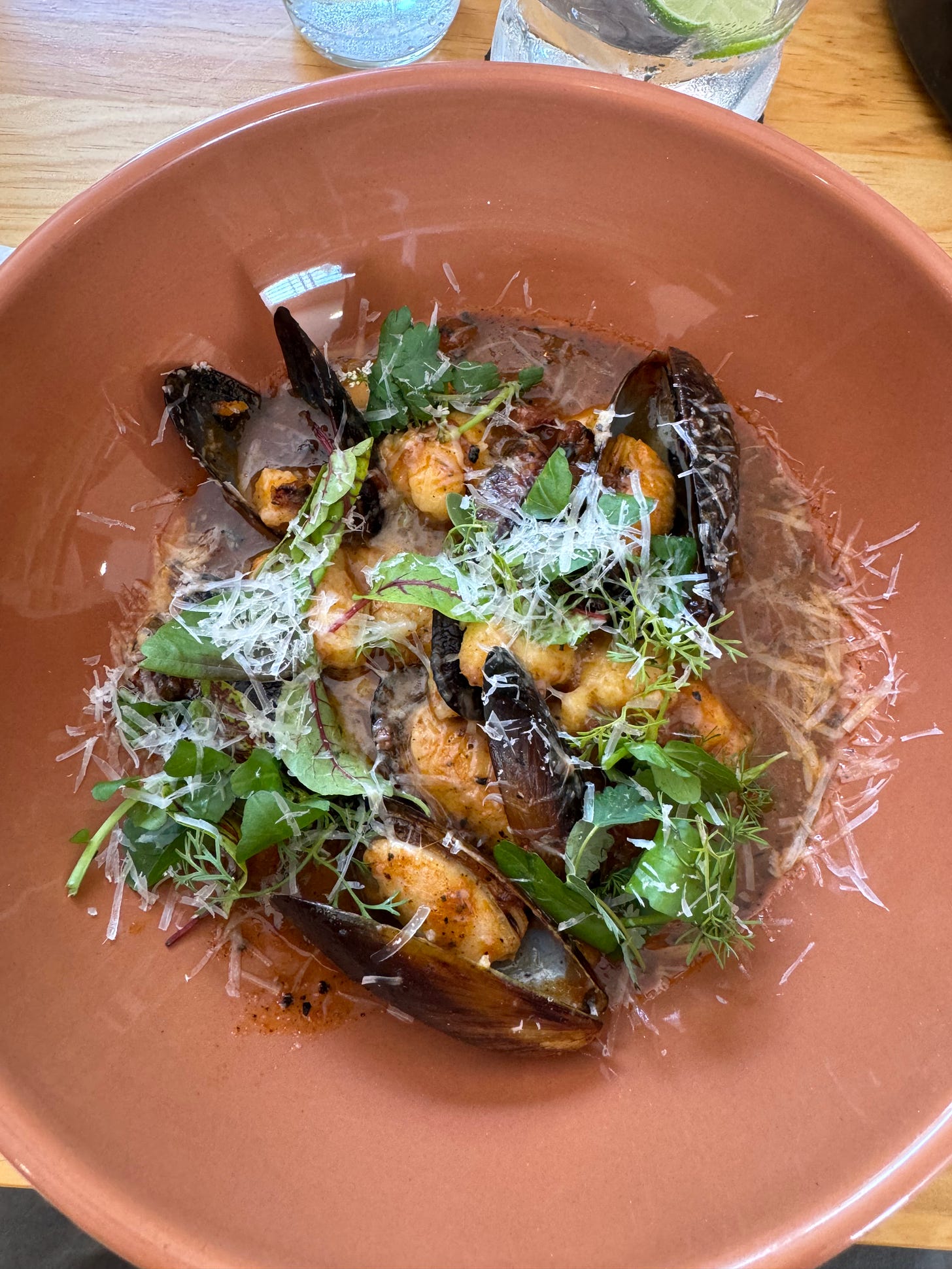 Gnocchi with greens and mussels in a round bowl.