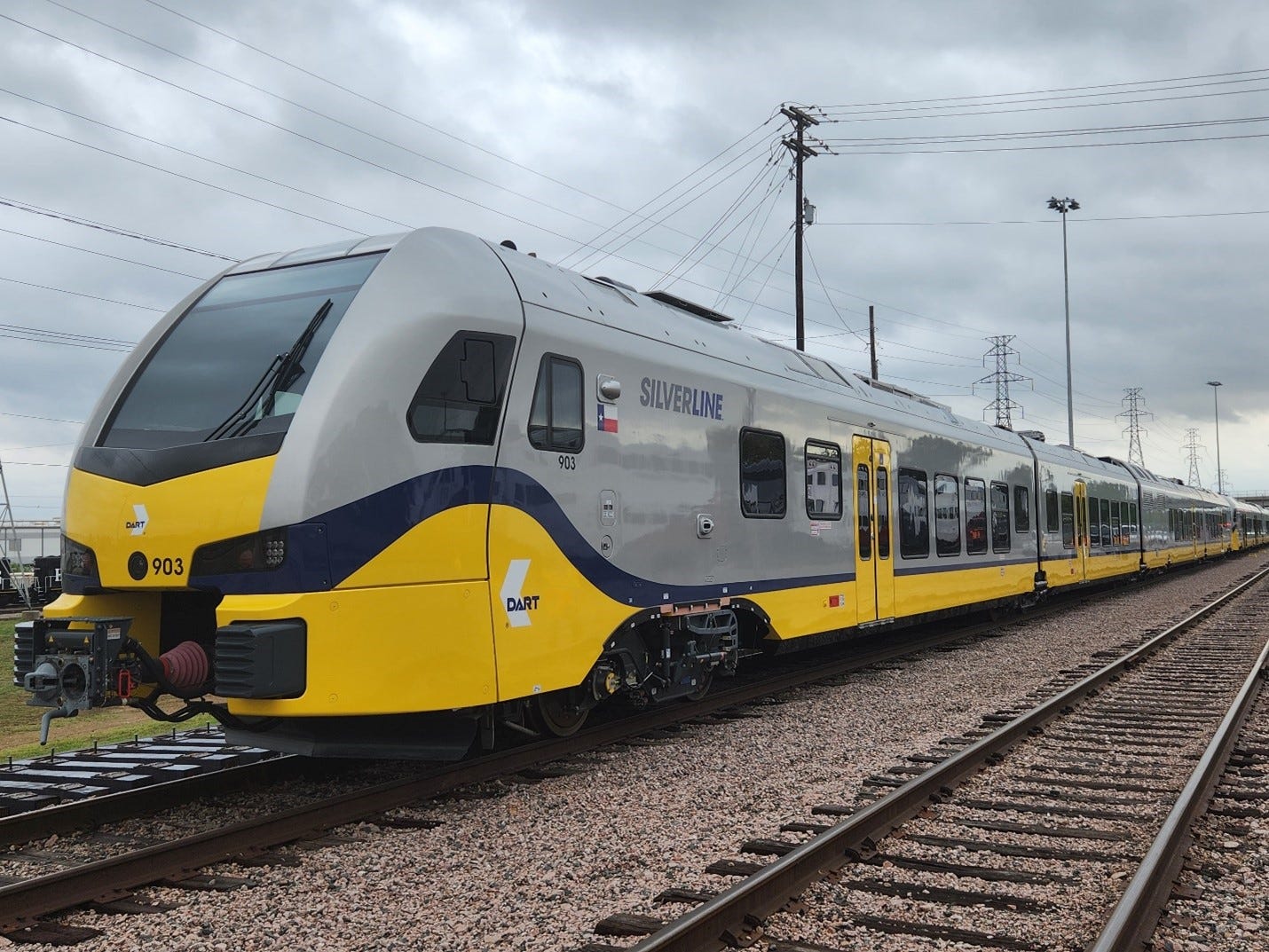 A yellow and silver train bearing the DART logo