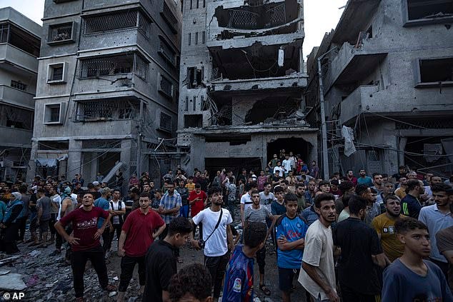 Palestinians watch others looking for injured in the rubble of a destroyed residential building following an Israeli airstrike
