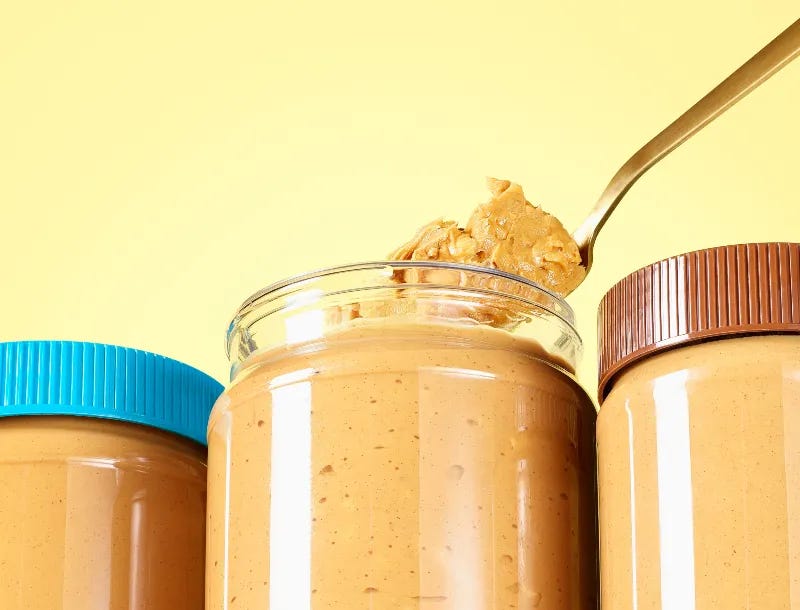Three full jars of peanut butter, one with a spoon digging out a bite.