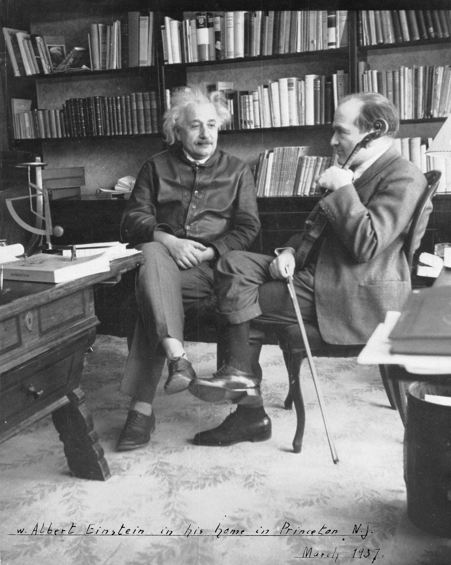 Two men sitting in a room with books. Two men sitting in a room with books.