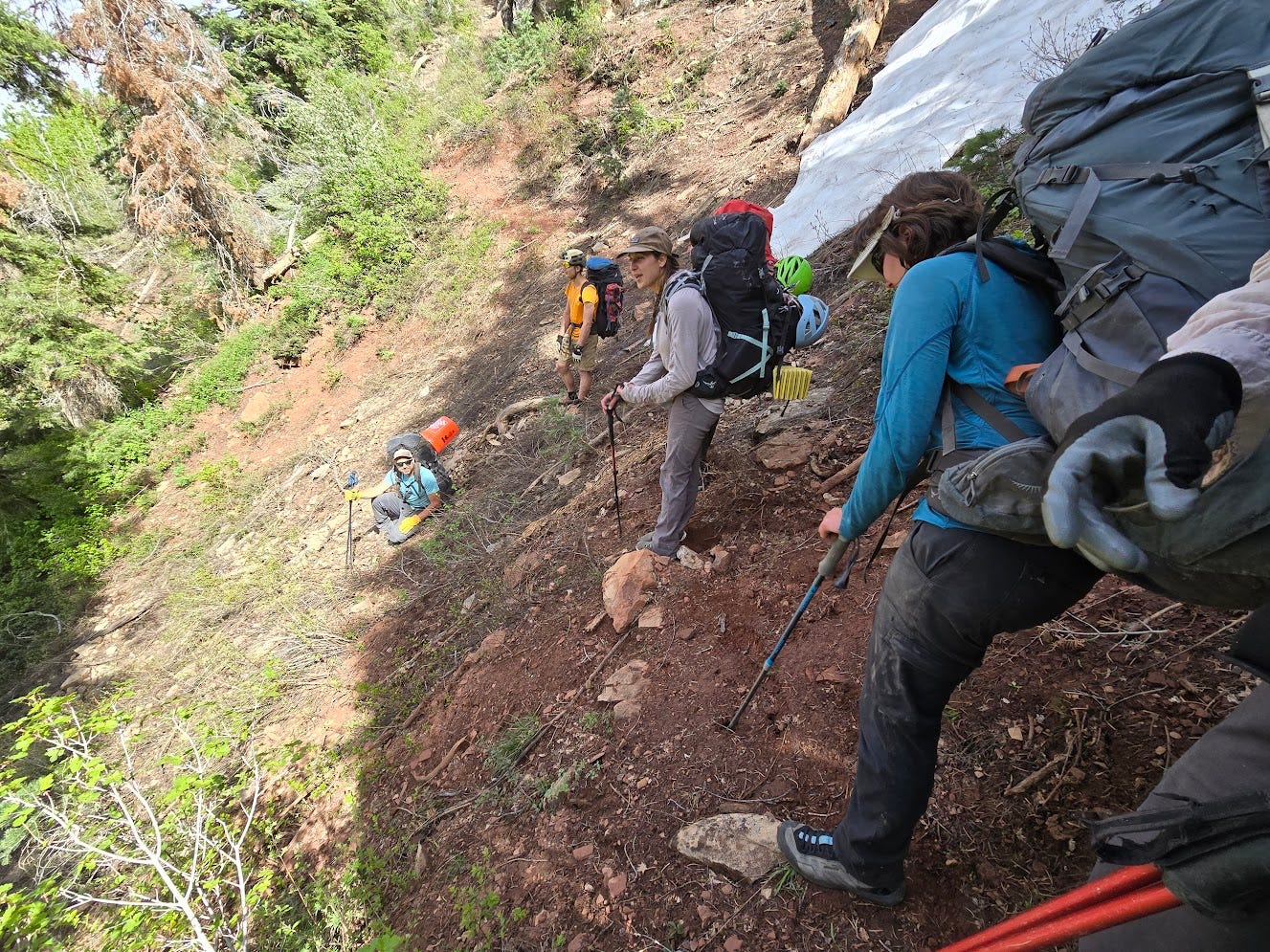 Several of us standing on a slope next to a snowpatch