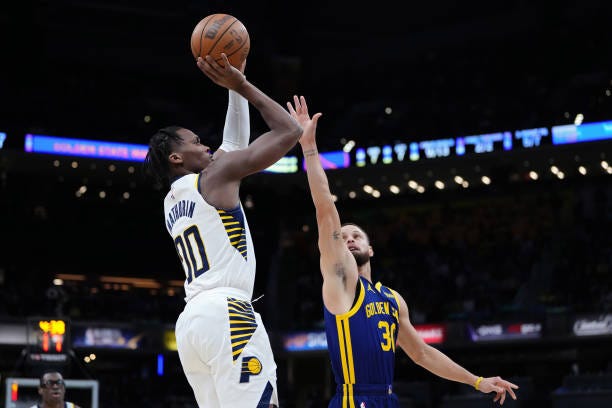 Bennedict Mathurin of the Indiana Pacers shoots against Stephen Curry of the Golden State Warriors in the first quarter at Gainbridge Fieldhouse on...