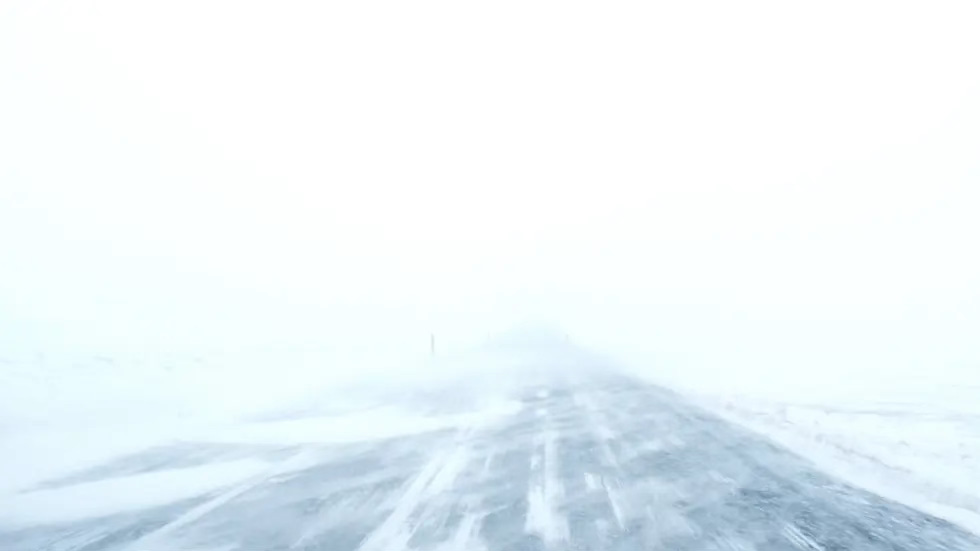 Whiteout snowstorm with a dark empty road.