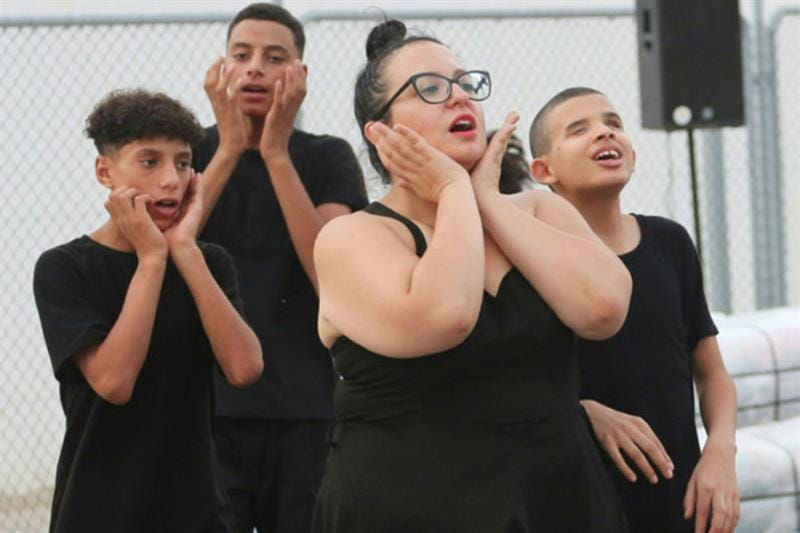 4 dancers wearing all black perform outside.
