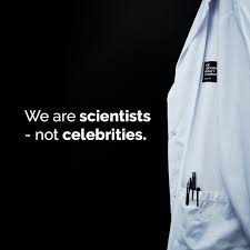 A close-up of a white lab coat with a pocket protector, displaying the text "We are scientists - not celebrities."