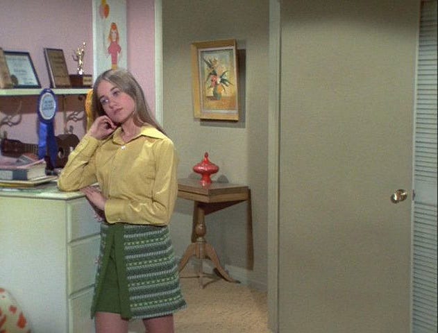 Marcia Brady ponders in a green skirt and yellow blouse.