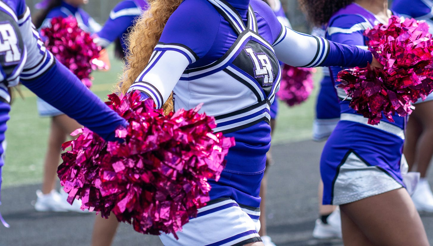 Black women cheerleaders with purple suits and magenta pom poms