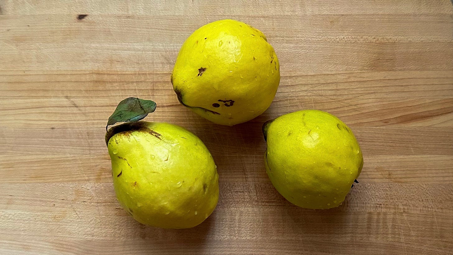 Photo of three ripe quince on a wooden cutting board.