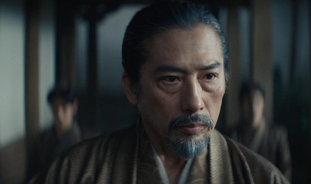 Hiroyuki Sanada in a screenshot from Shogun. He is wearing a brown robe and facing the camera with a serious expression