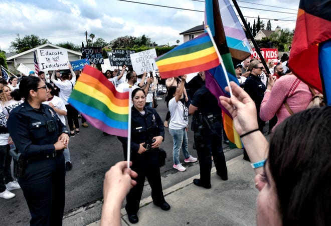LGBTQ counter-protesters wave Pride Flags as Los Angeles police officers separate them from protesters at the Saticoy Elementary School in the North Hollywood section of Los Angeles on Friday, June 2, 2023. Police officers separated the groups Friday outside a Los Angeles elementary school that has become a flashpoint for Pride Month events and activities across California. People protesting a planned Pride Month assembly outside the Los Angeles Unified School District's Saticoy Elementary School wore T-shirts imprinted with "Leave our kids alone" and carried signs with slogans such as "Parental Choice Matters" and "No Pride in Grooming." (AP Photo/Richard Vogel)