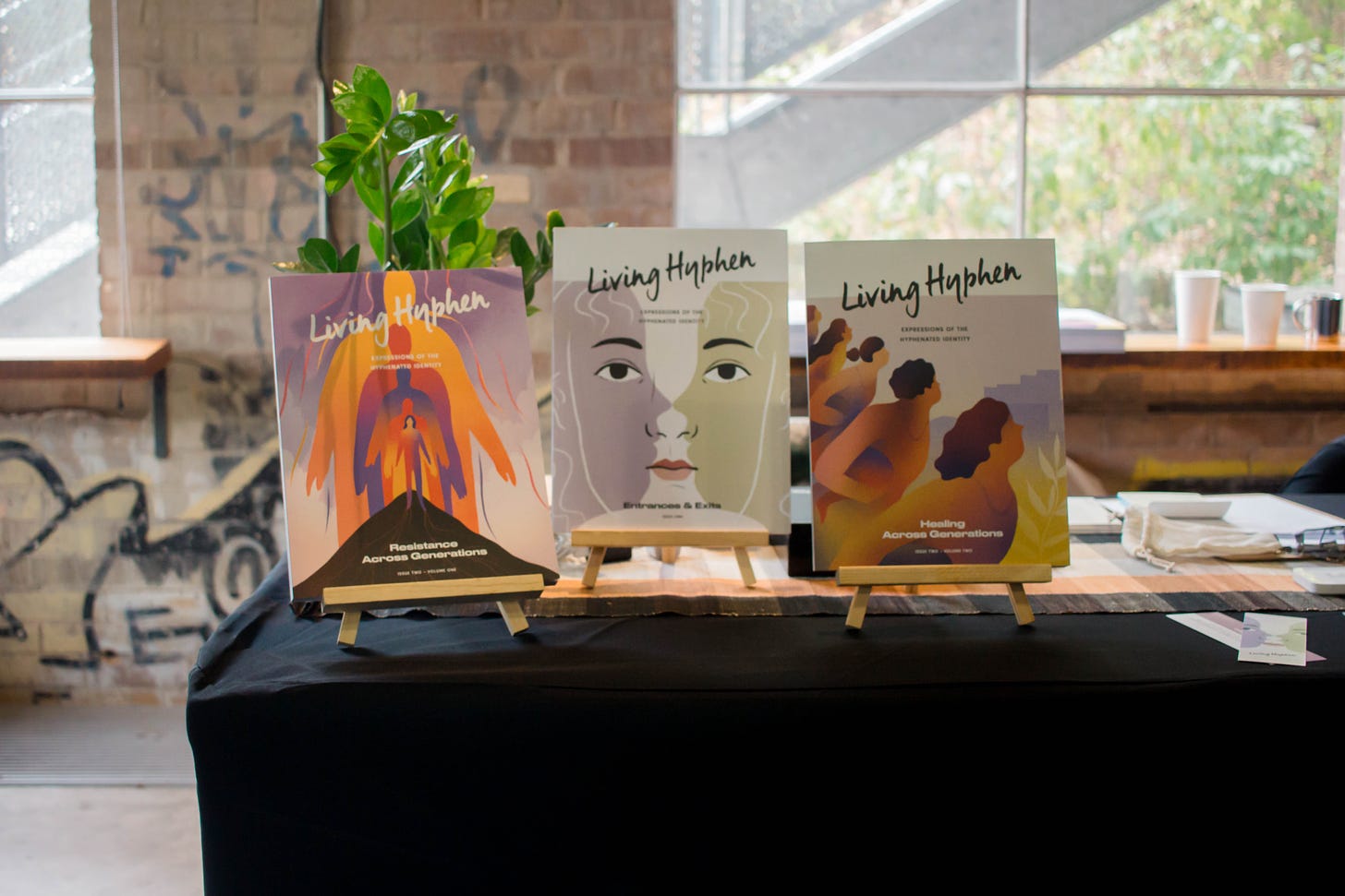 Three issues of Living Hyphen magazine standing upright on display.