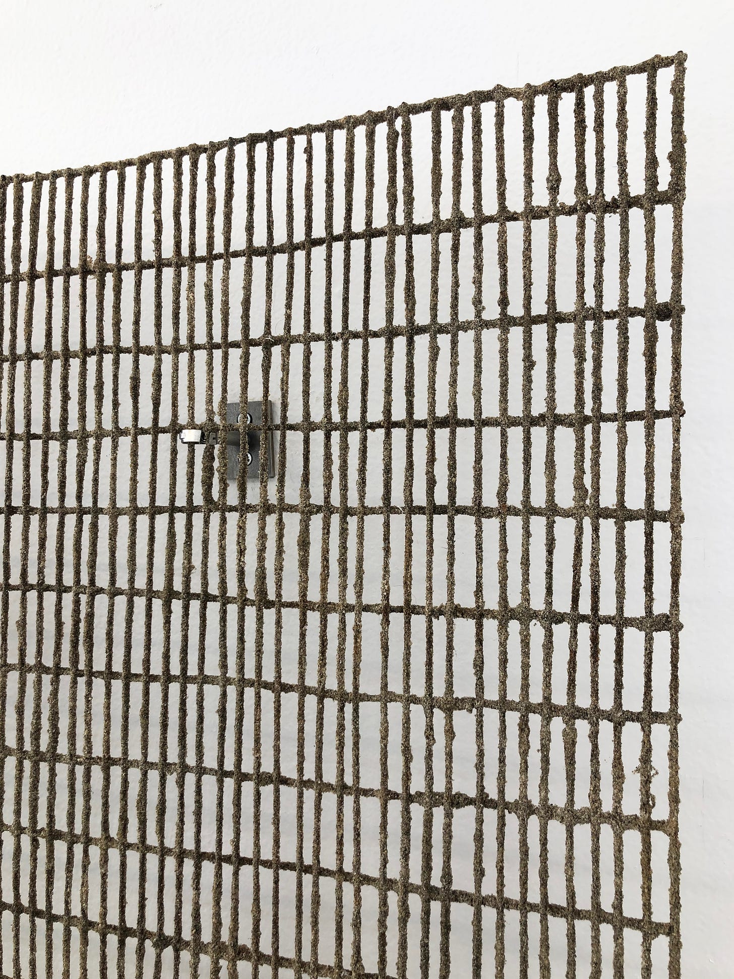 Close-up of sand brazed steel grid fixed to a white wall