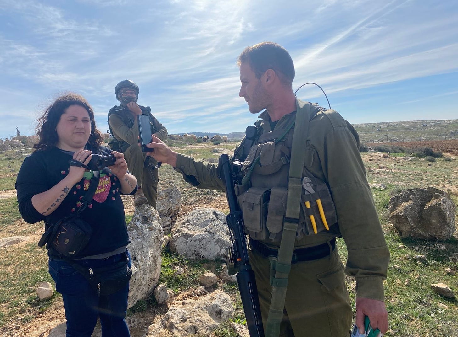 Photo of the interviewee with a camcorder and an IDF solder holding a phone in her face