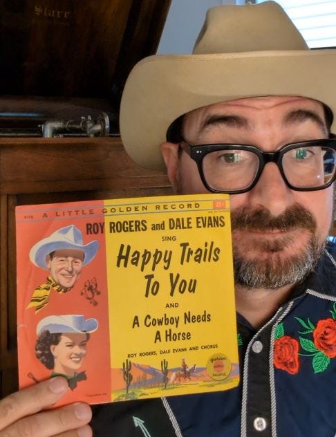 man in a cowboy hat holding a record 'Roy Rogers and Dale Evans sing Happy Trails to You'